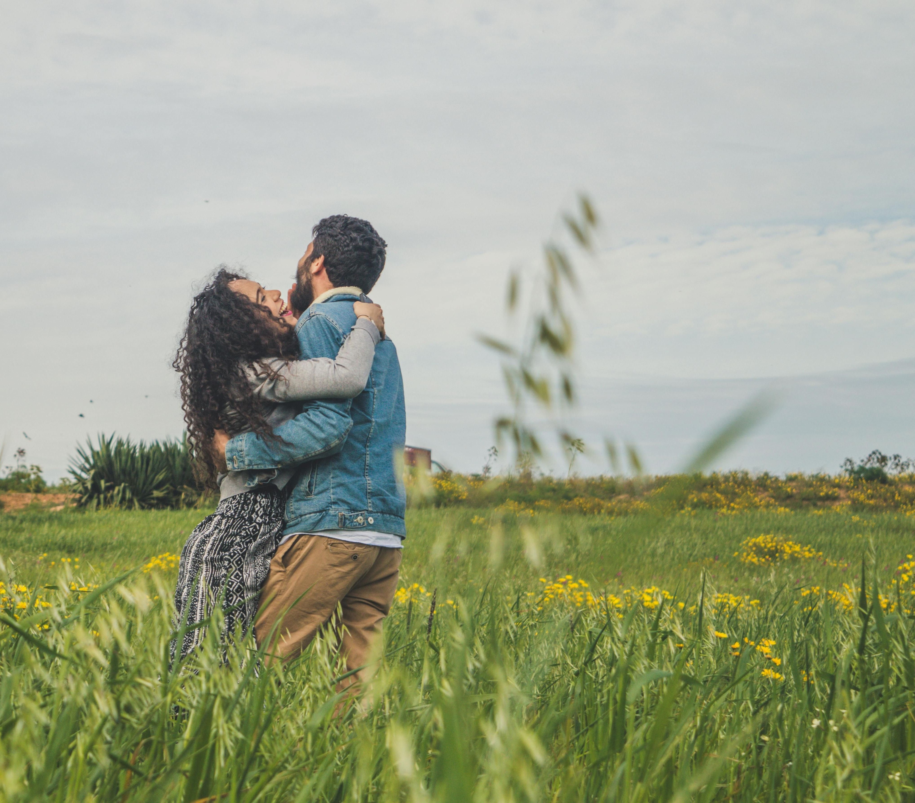 Couple hugging on green field